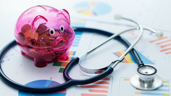 Stethoscope and piggybank on top of print-outs of bar charts